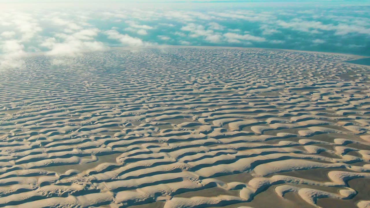 Wide dune pattern stretching toward a cloudy horizon.