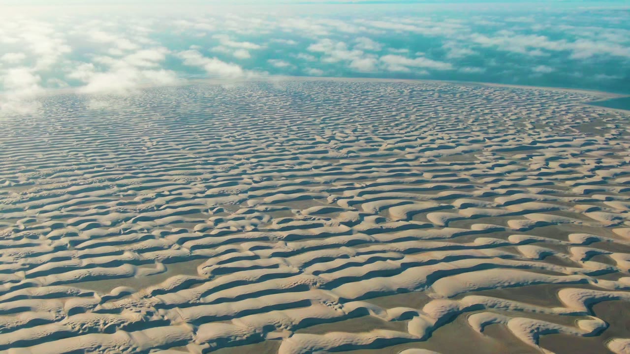 Rippled sand forms fill most of the Guerrero Negro frame while white clouds sit above a narrow horizon, with no visible people or structures.