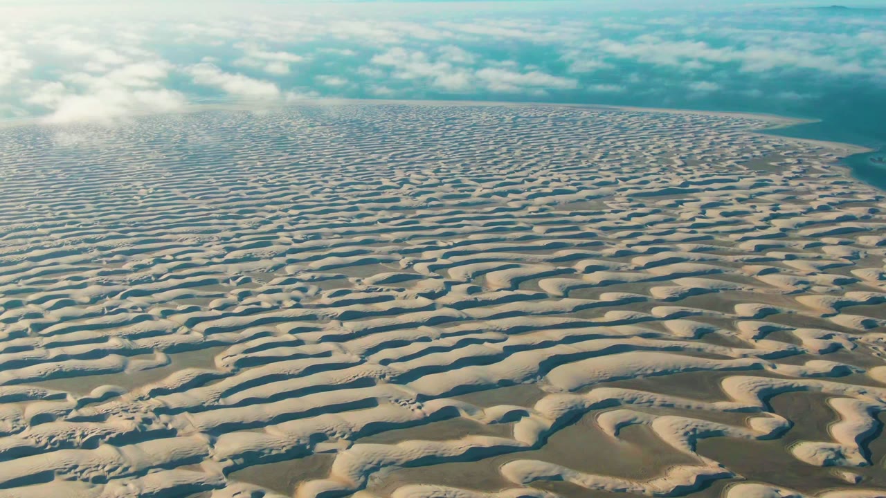 Mid-clip aerial frame shows rippled beige dunes across Guerrero Negro with stronger shadow bands in the foreground and no visible people.