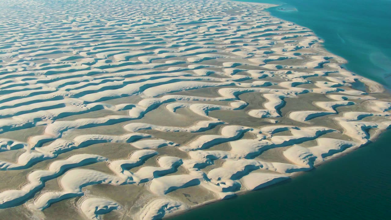 Patterned sand ridges continue along a blue shoreline.