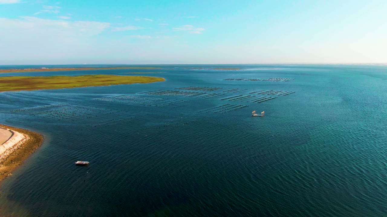 Small boats on rippled turquoise water with shoreline and distant green land