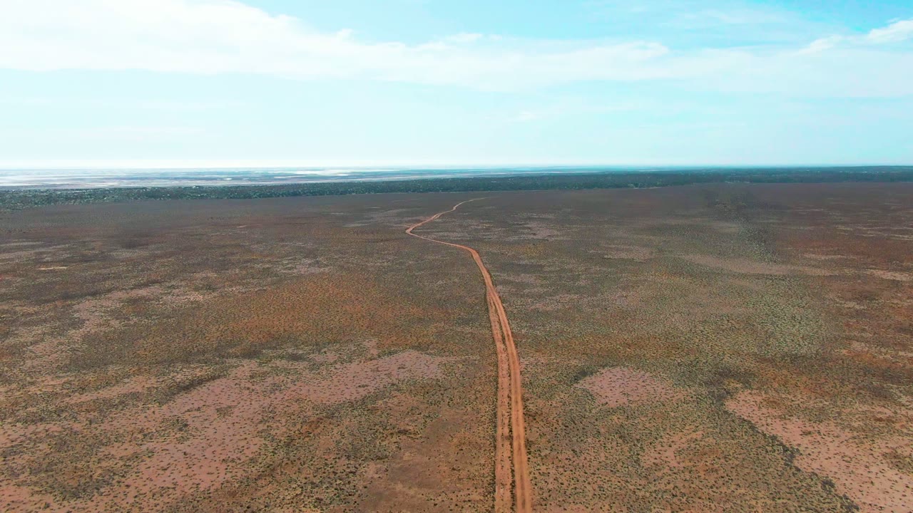 Aerial view of red track crossing dry plains toward the horizon.