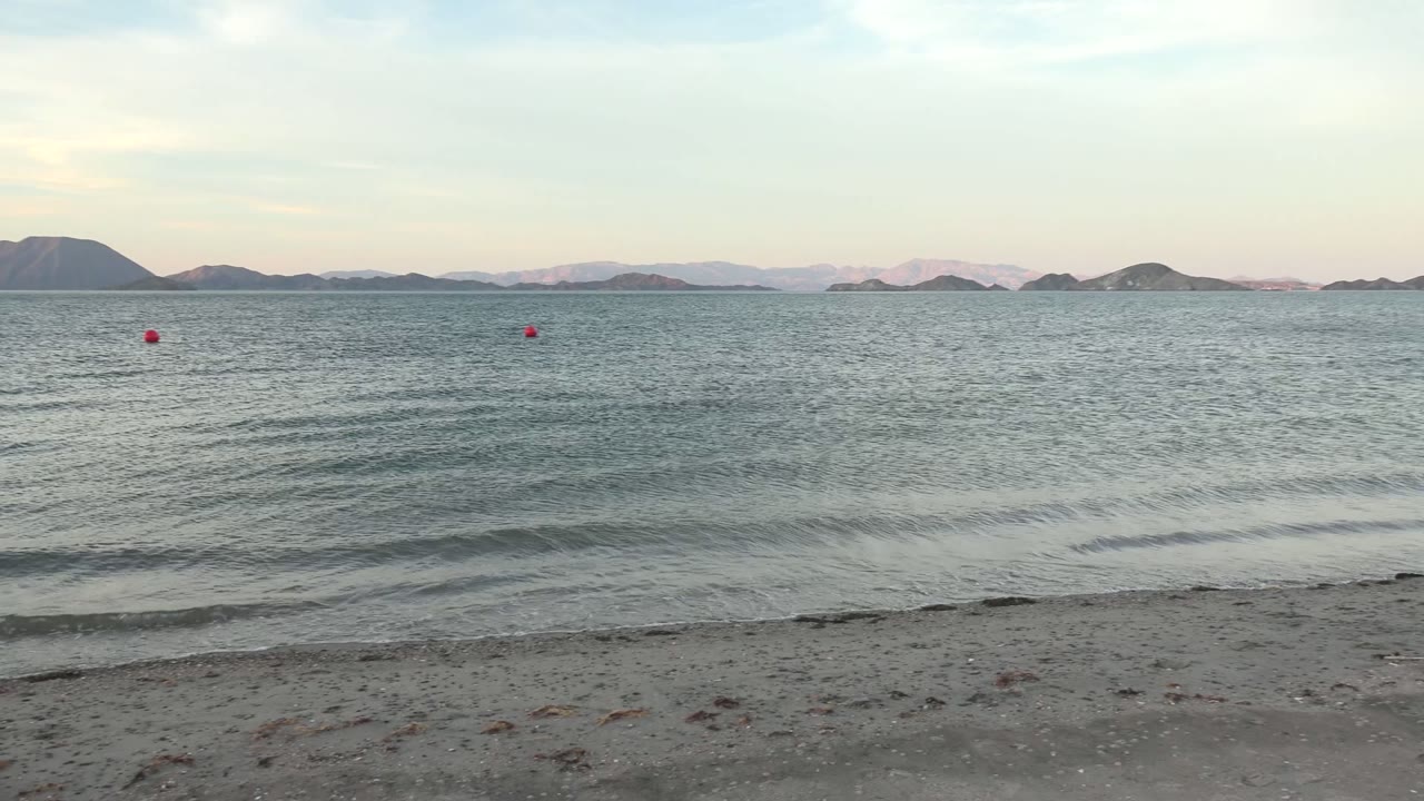 Low waves crossing a sandy shore with buoys offshore
