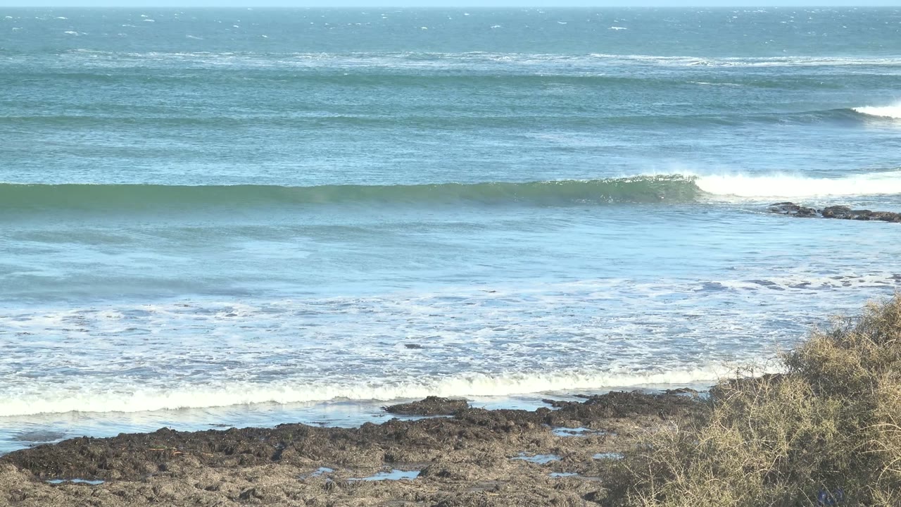 Ocean swell cresting near rocky shoreline.