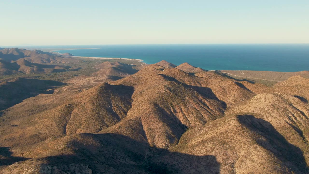 Sunlit desert ridges with ocean in the distance