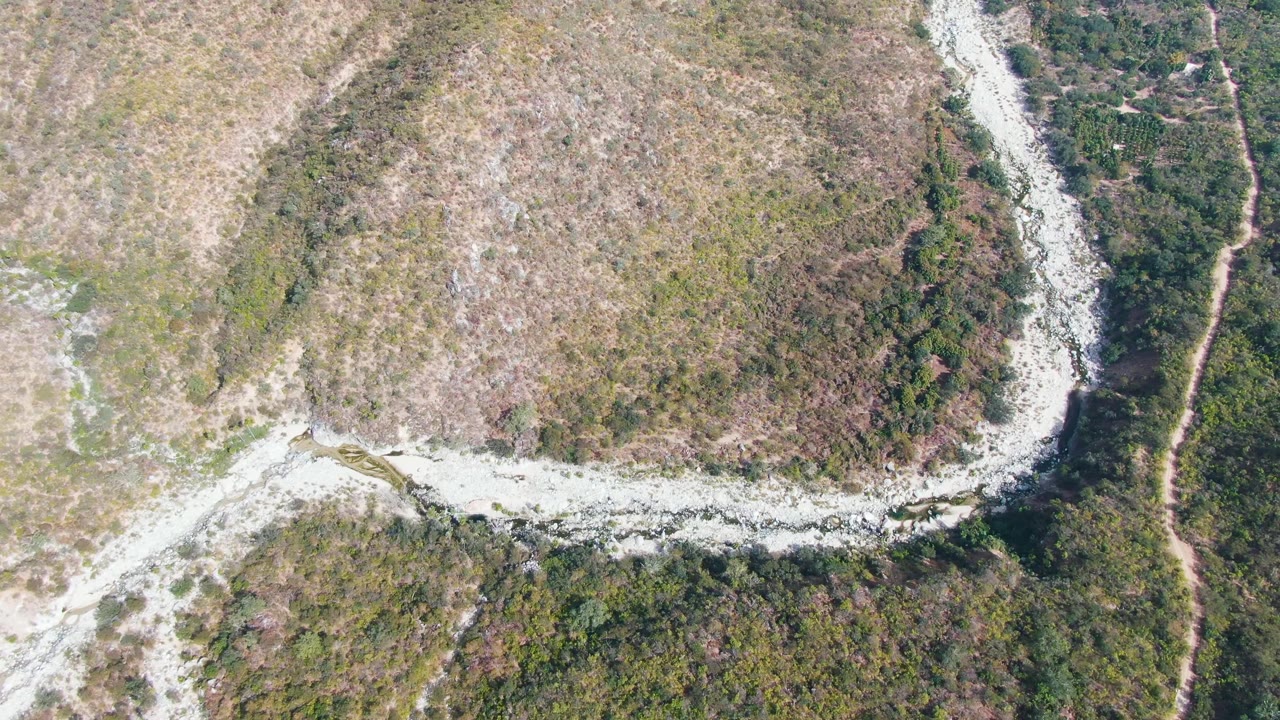 Top-down frame from San Dionisio, Baja California Sur showing a winding pale path crossing scrub-covered terrain with dry brown patches and no visible people.