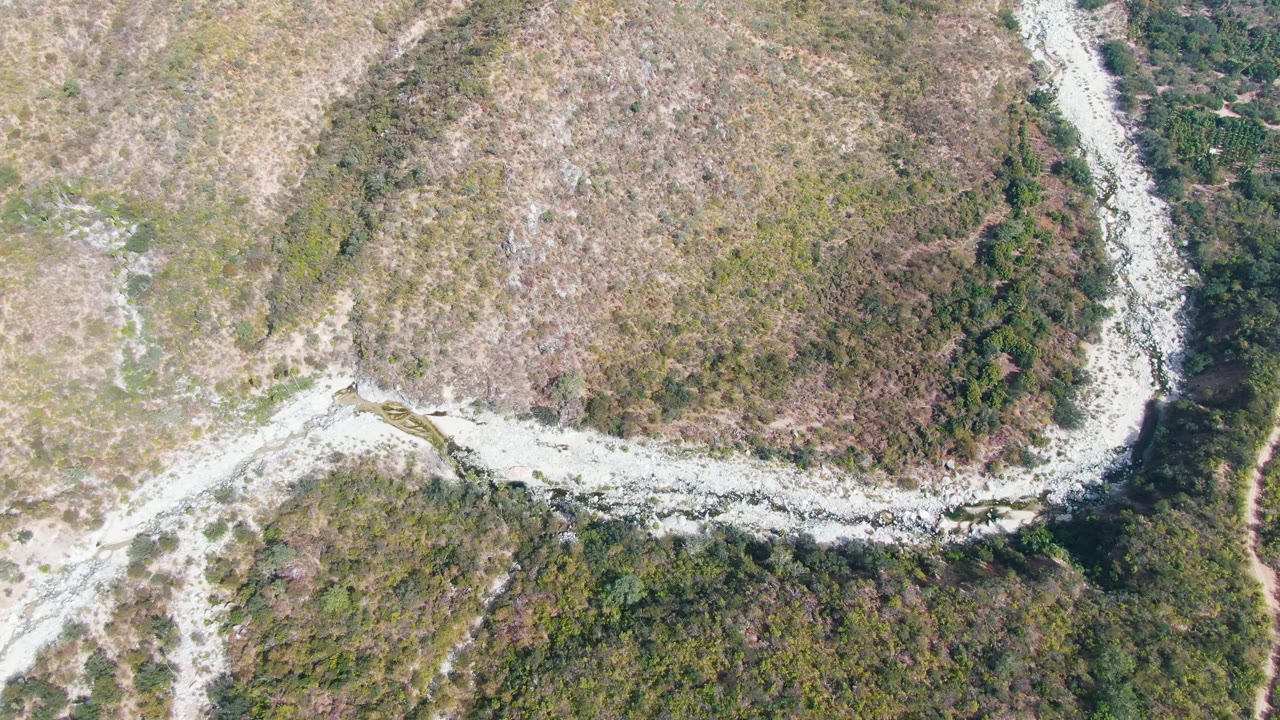 Aerial frame in San Dionisio, Baja California Sur with the pale path curving across scrubby brown ground beside a darker green vegetation strip, with no visible people.