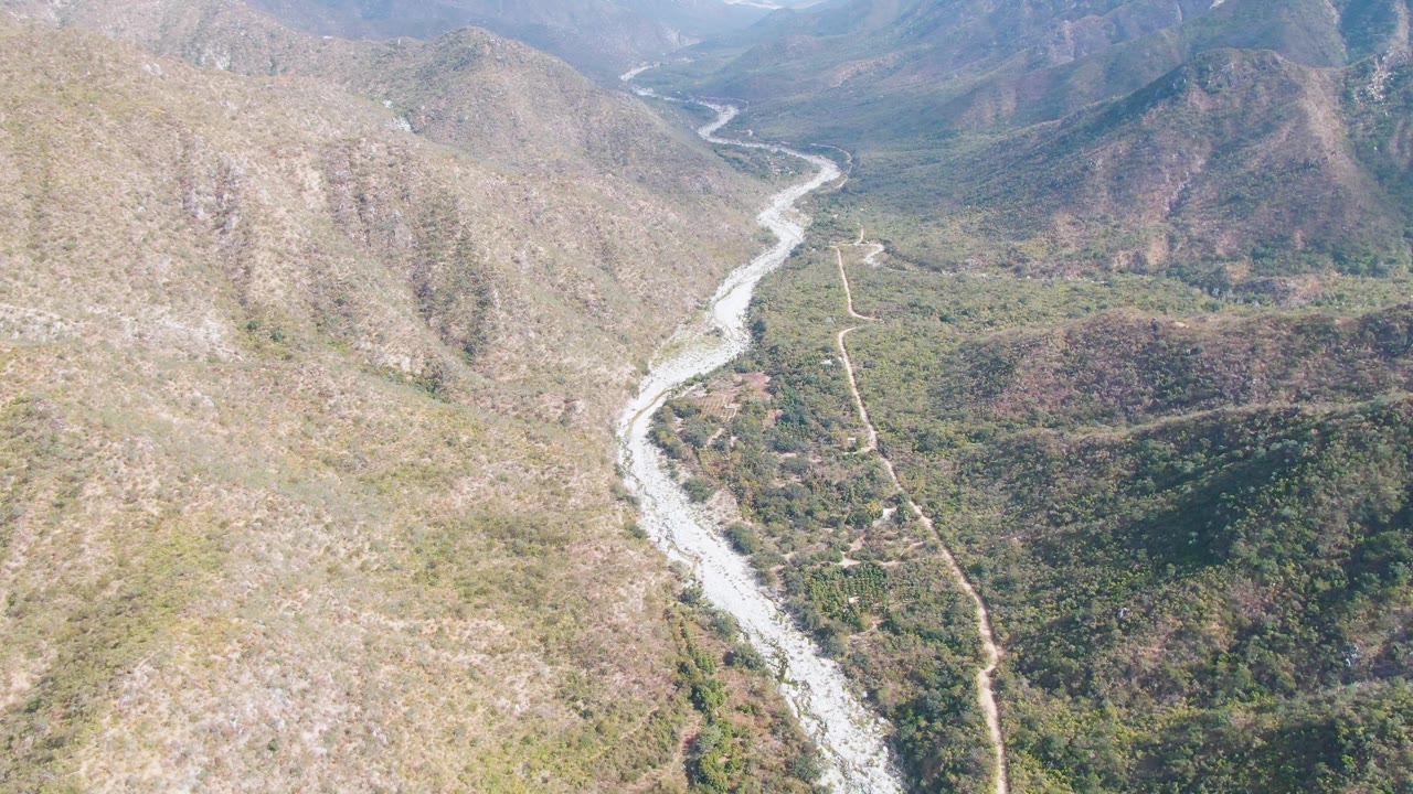 A later aerial view of San Dionisio, Baja California Sur, with more left hillside visible above the winding river and no visible people.