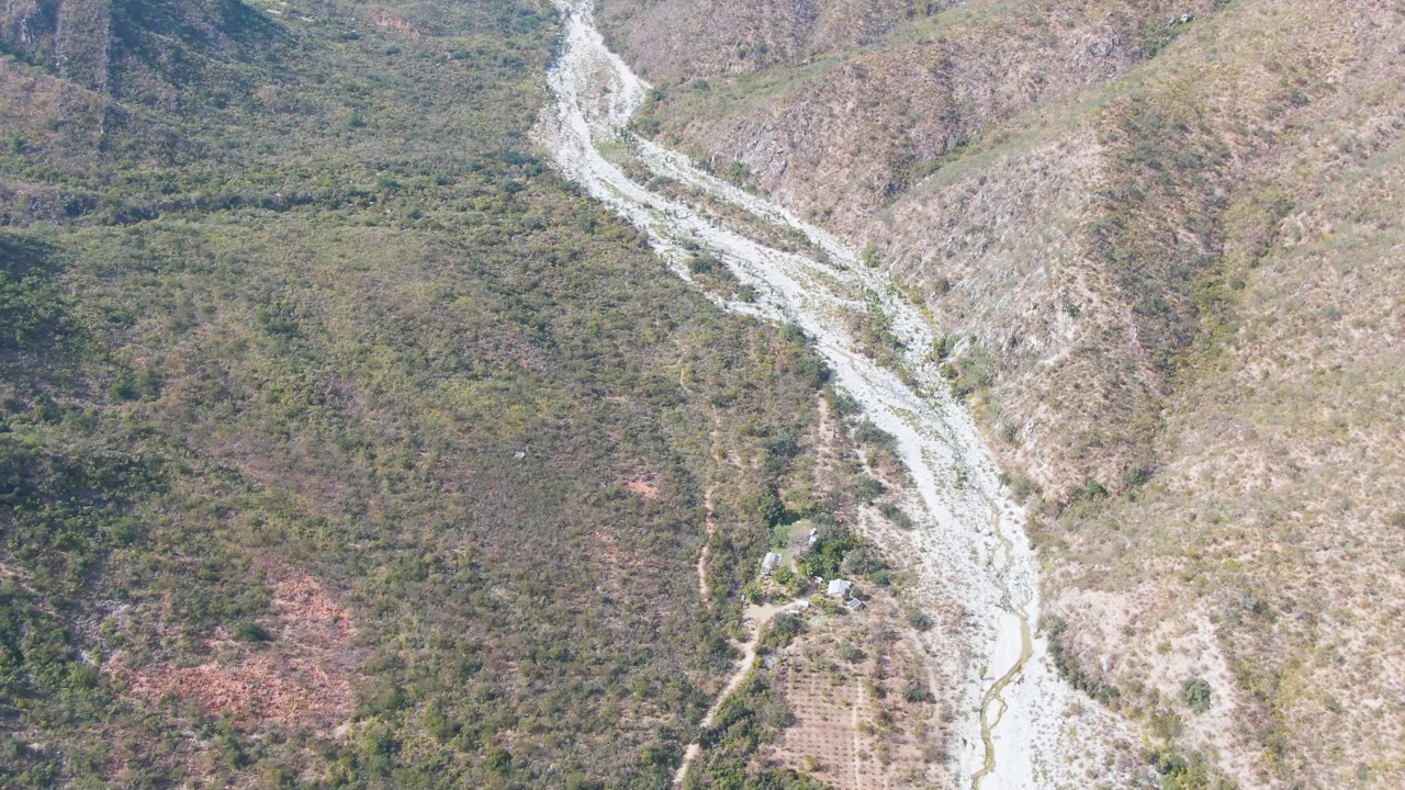 Overhead valley view with riverbed, dirt tracks, and scrub