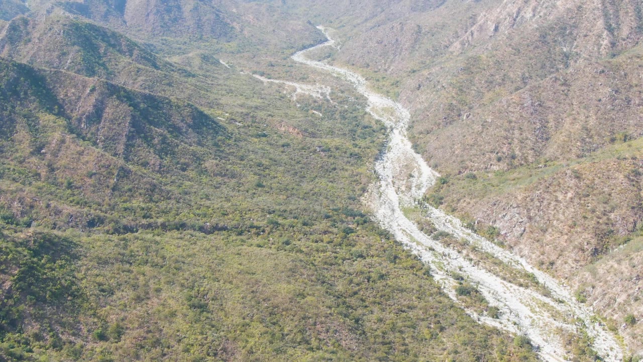 Aerial landscape of a riverbed branching through a rocky green valley.