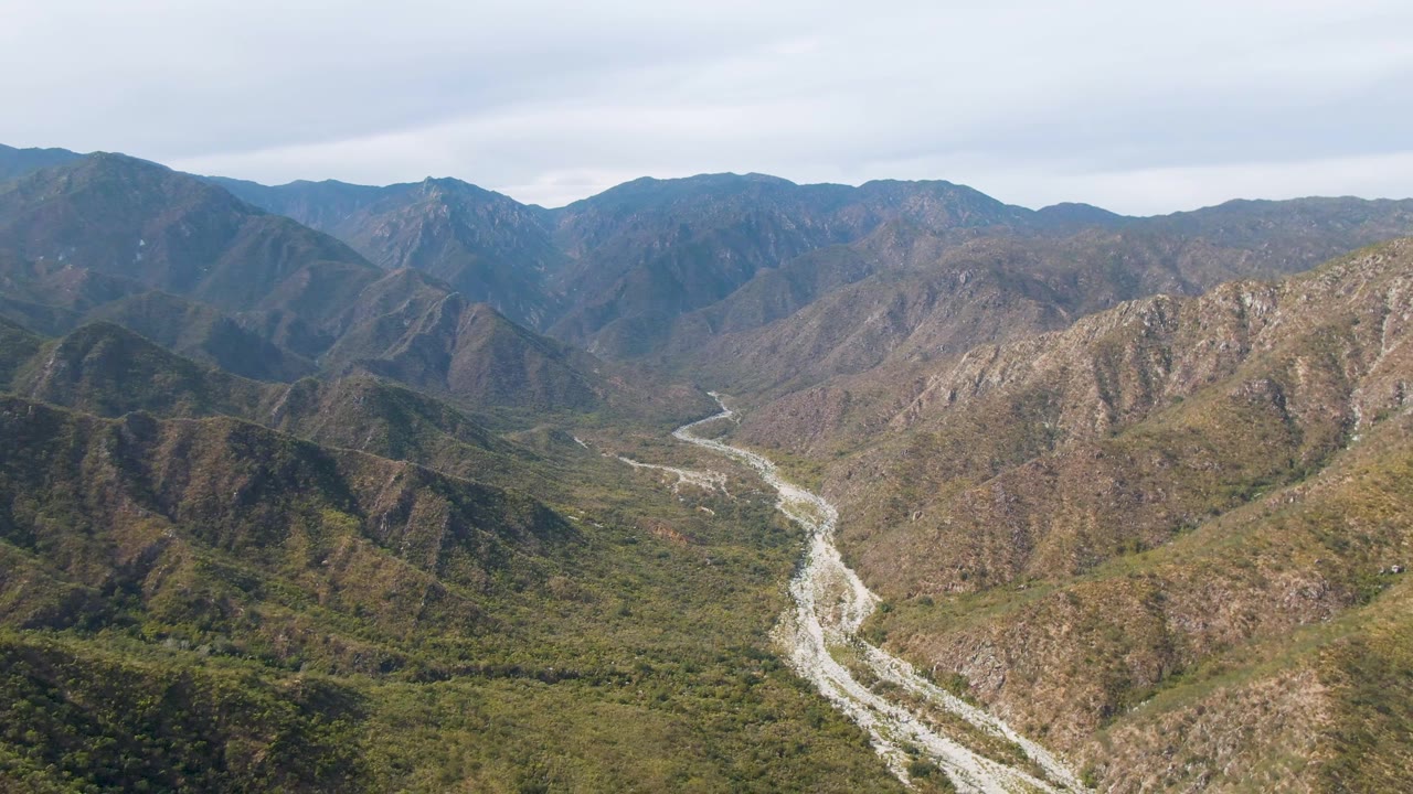 Aerial shot of a river curving away through steep hills.