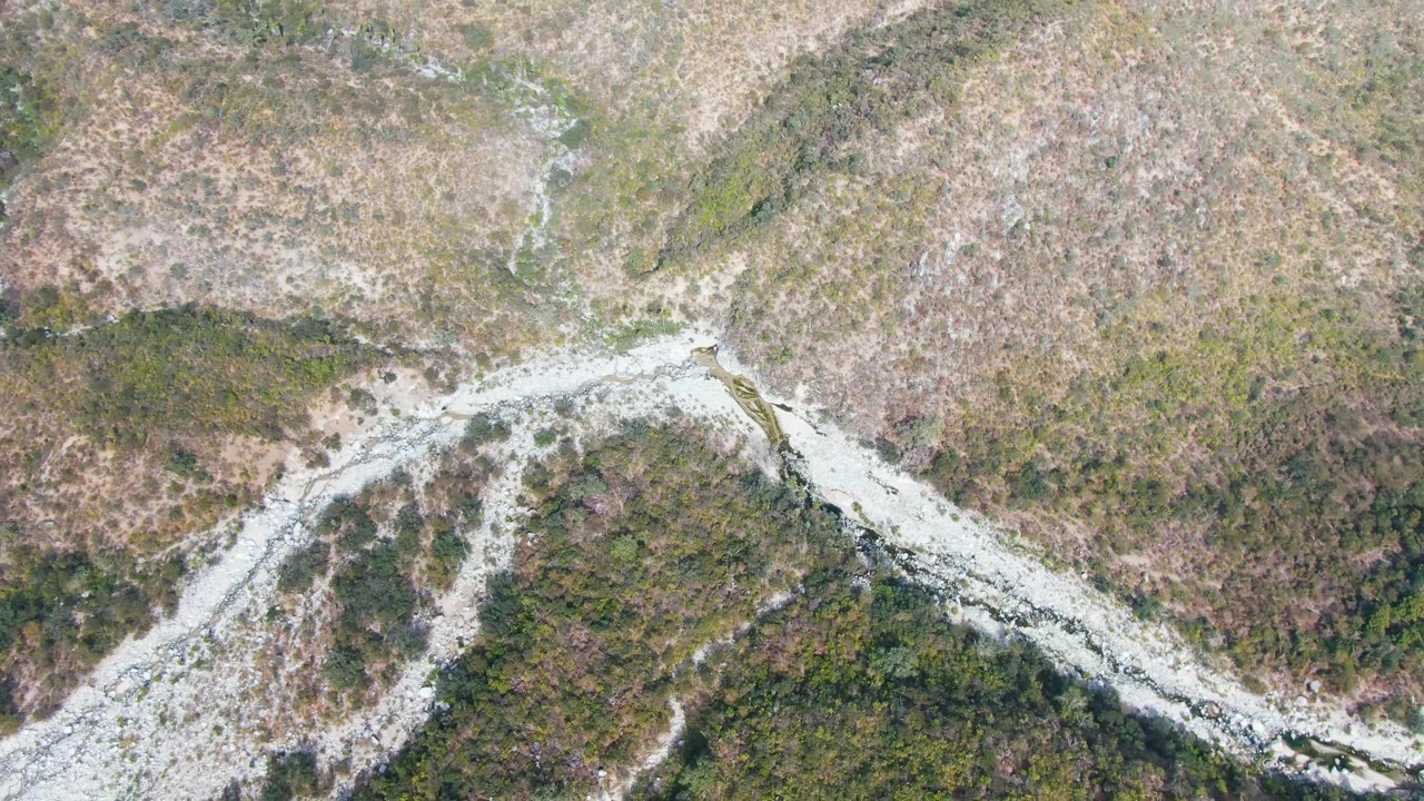 Aerial frame over San Dionisio, Baja California Sur, with a diagonal light mountain track bordered by brown scrub and darker green vegetation, no visible people.