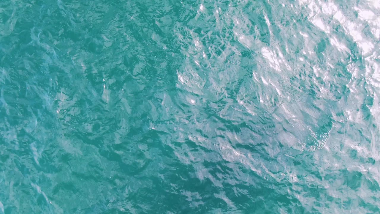 Turquoise water surface crossed by pale foam