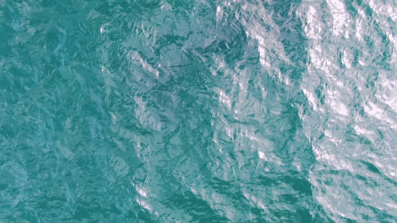 Turquoise ocean surface with ripples and bright white highlights