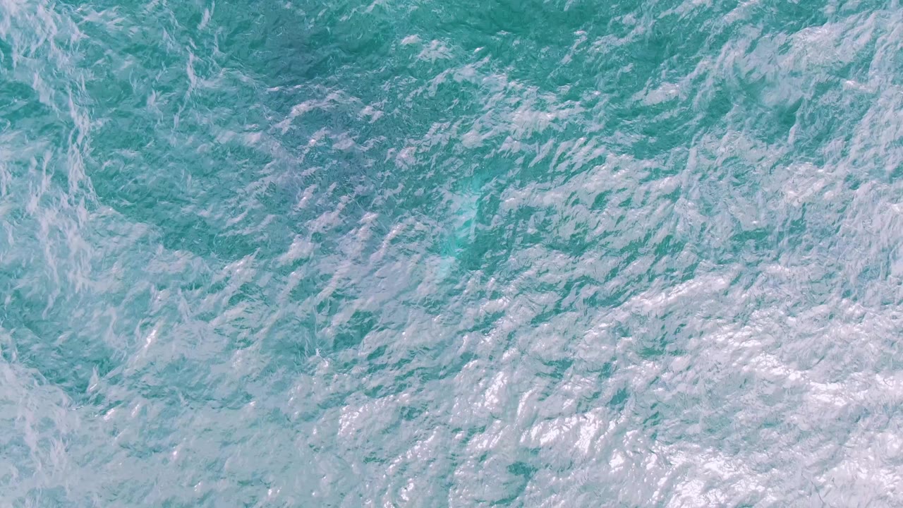 Rippling turquoise water fills the frame at Shipwrecks, Baja California Sur, with scattered white sea foam and no visible people.