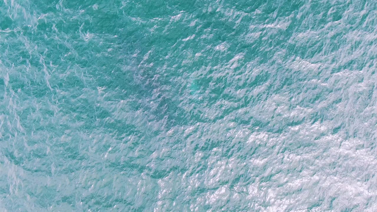 Turquoise water with scattered white wave foam.
