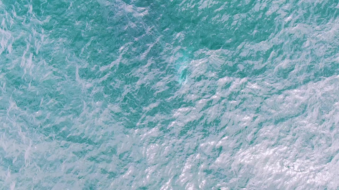 Turquoise ocean surface with white foam patterns.