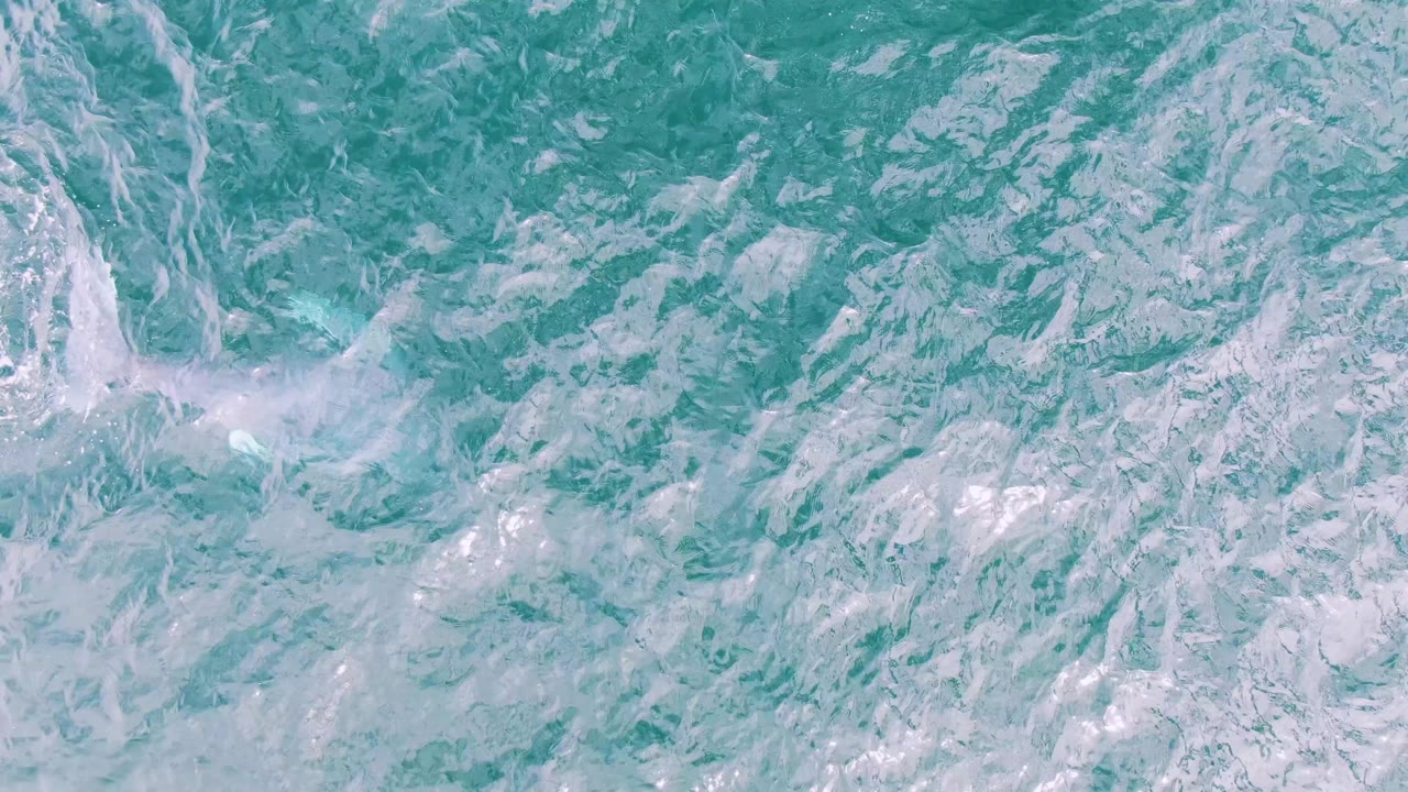White splash trail across turquoise ocean surface
