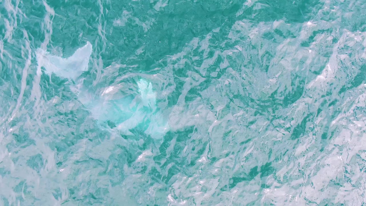 Turquoise ocean surface with white foam and ripples