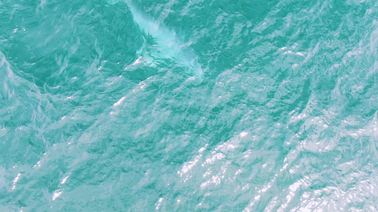 Overhead view of clear turquoise ocean water at Shipwrecks, Baja California Sur, with wind-textured ripples and no visible people.