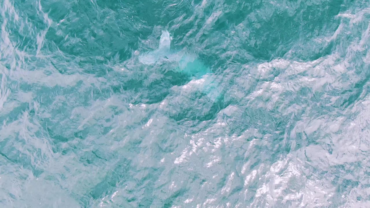 Turquoise ocean surface at Shipwrecks, Baja California Sur, with denser white foam texture near the center and no visible people, boats, or shoreline.