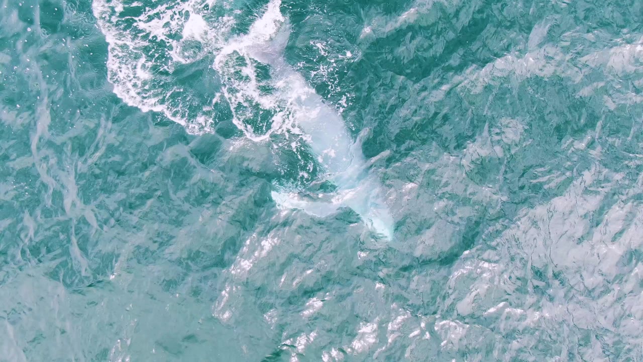 Turquoise ocean surface with white foam and ripples