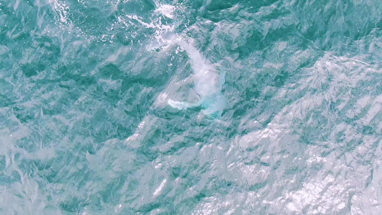 Turquoise and pale blue ocean surface at Shipwrecks, East Cape, Baja California Sur, with thin foam streaks and no visible people.