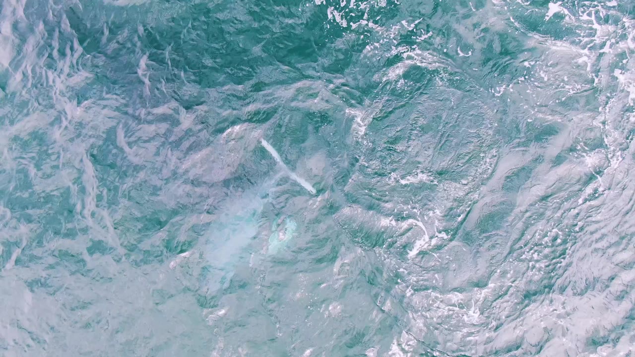 Foam streaks and uneven turquoise surface texture fill the frame at Shipwrecks, Baja California Sur, Mexico as the whale is no longer visible and no people appear.