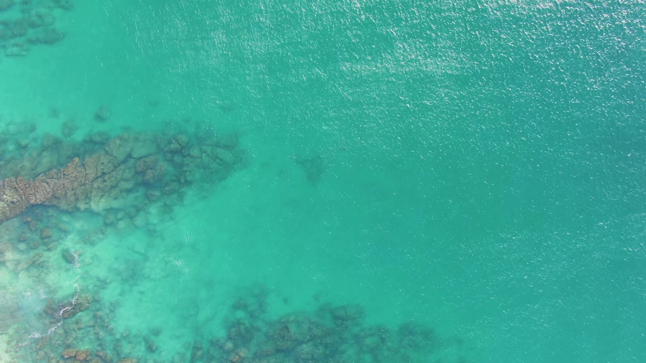 Overhead turquoise water with reef shapes beneath the surface.
