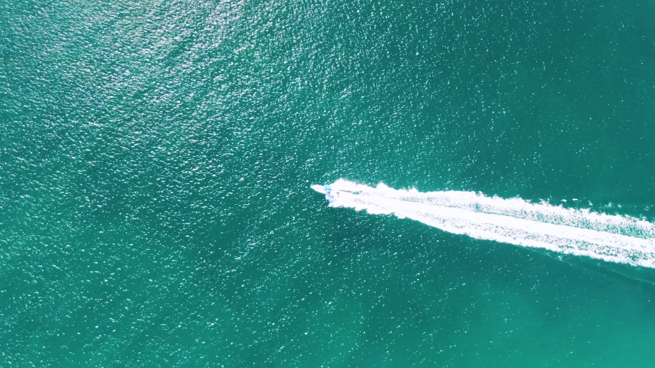 Speedboat crossing turquoise ocean water with a white wake