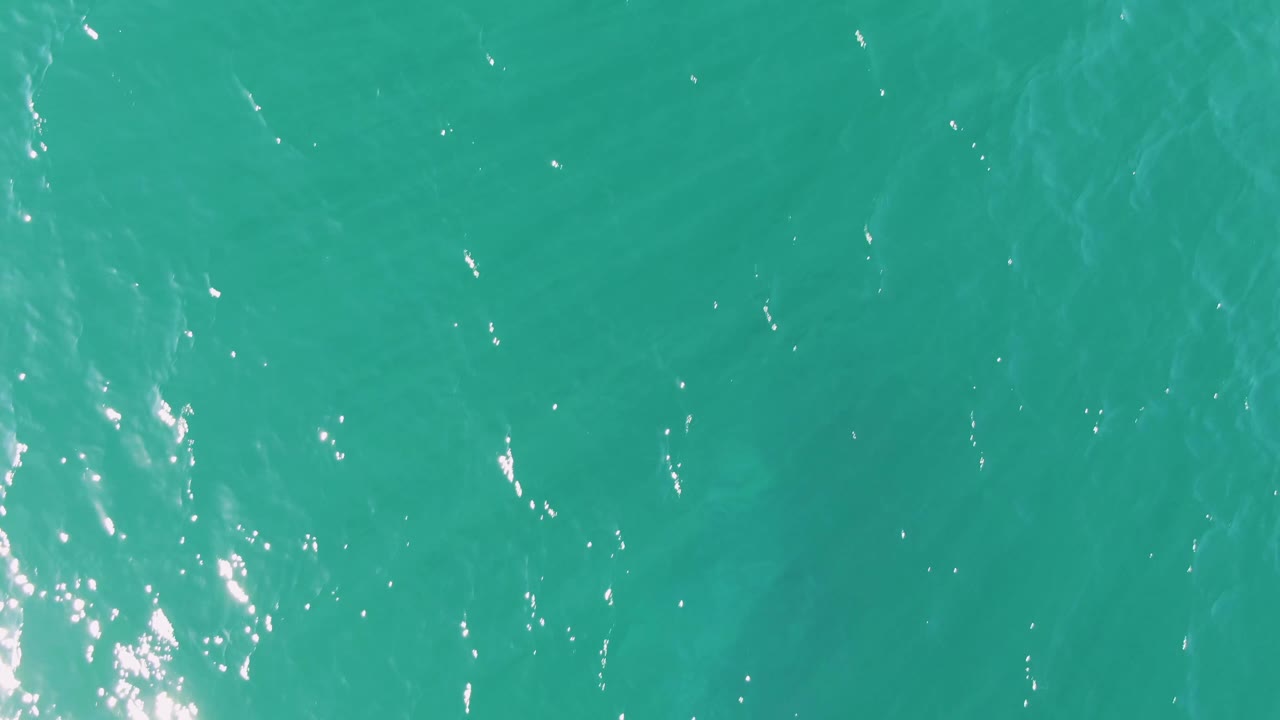 A frame of Buzzards Beach ocean surface with turquoise ripples, a taller streak of white shimmer through the center area, and no visible people.