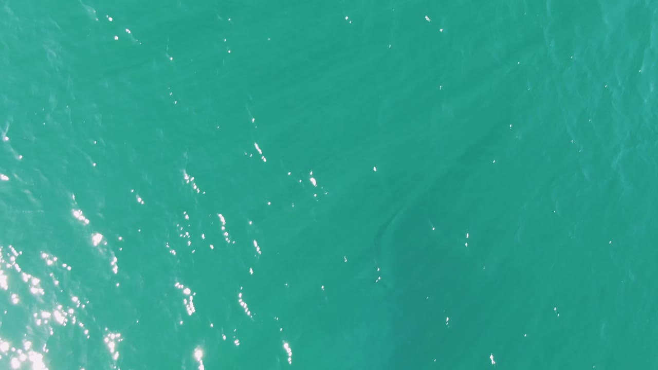 Mid-clip frame of turquoise ocean at Buzzards Beach in Baja California Sur, with scattered sparkles across the rippled surface and no visible people.