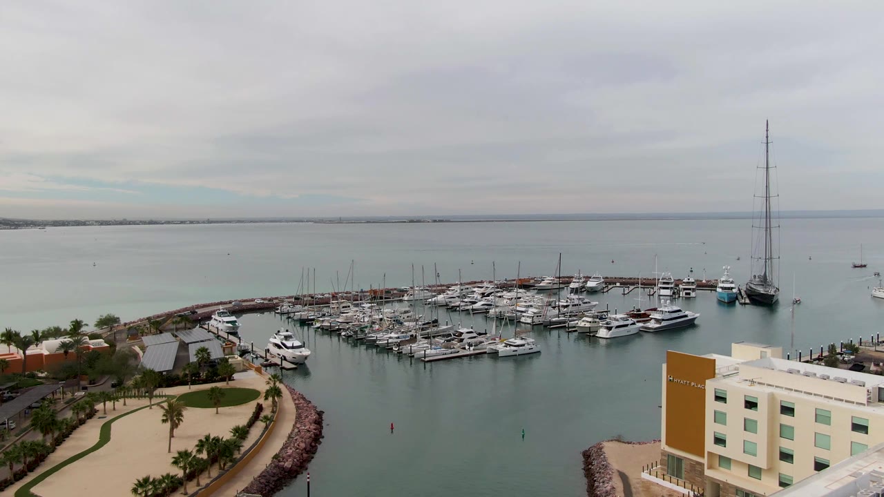 Aerial marina view with boats clustered around docks and a large sailboat near the right side.