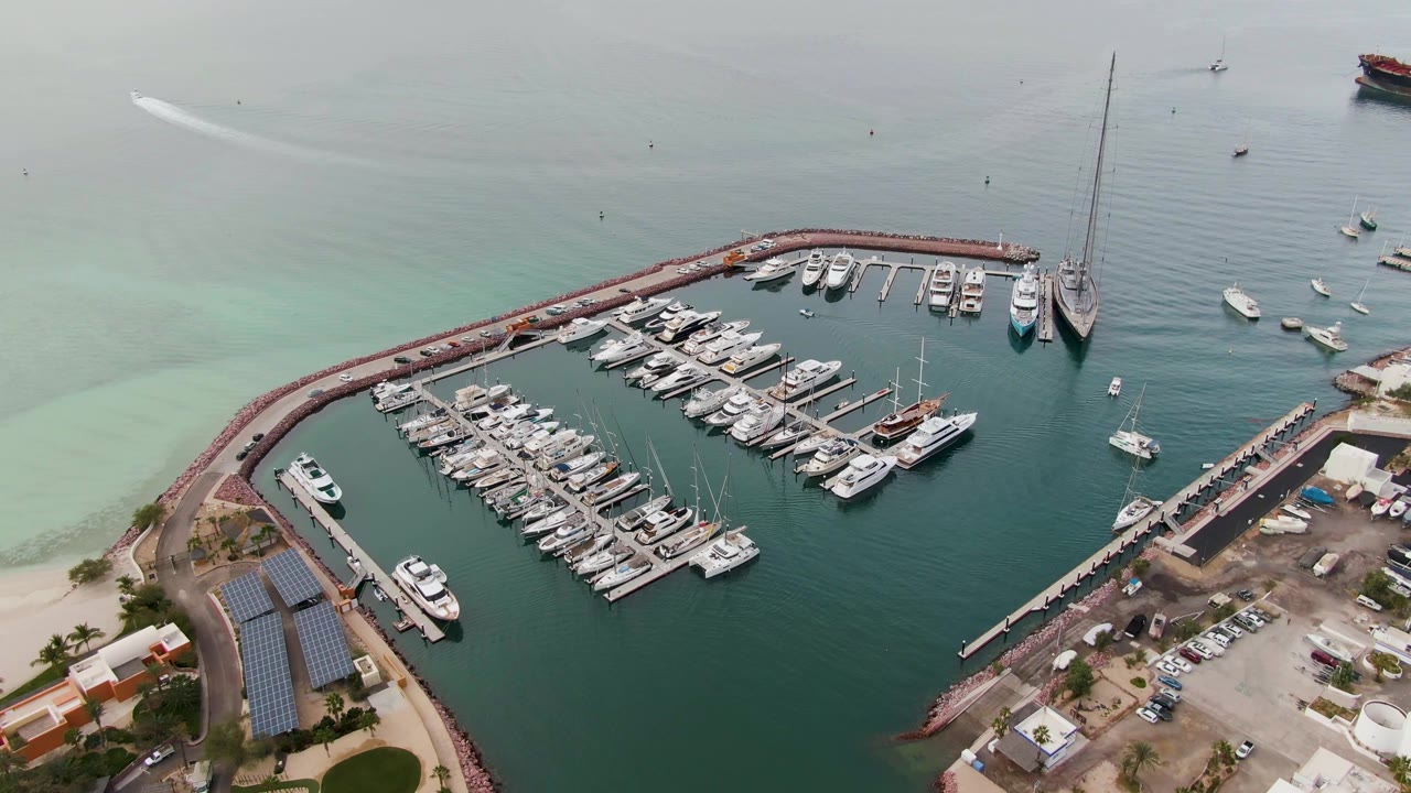 Aerial view of a marina with a boat wake across calm water.