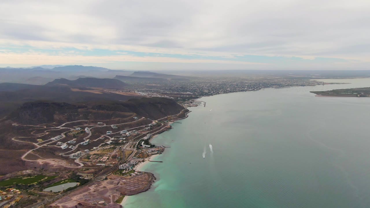 Aerial coastal landscape with turquoise shallows and distant city