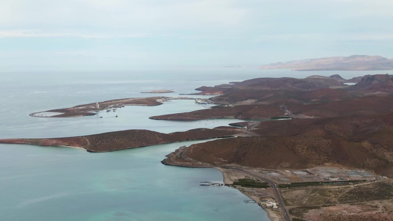 Aerial coastline with rocky islands, shallow sea, and dry terrain.