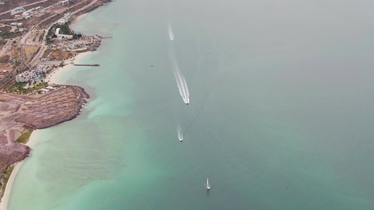 Aerial shoreline with turquoise shallows and several boats offshore.