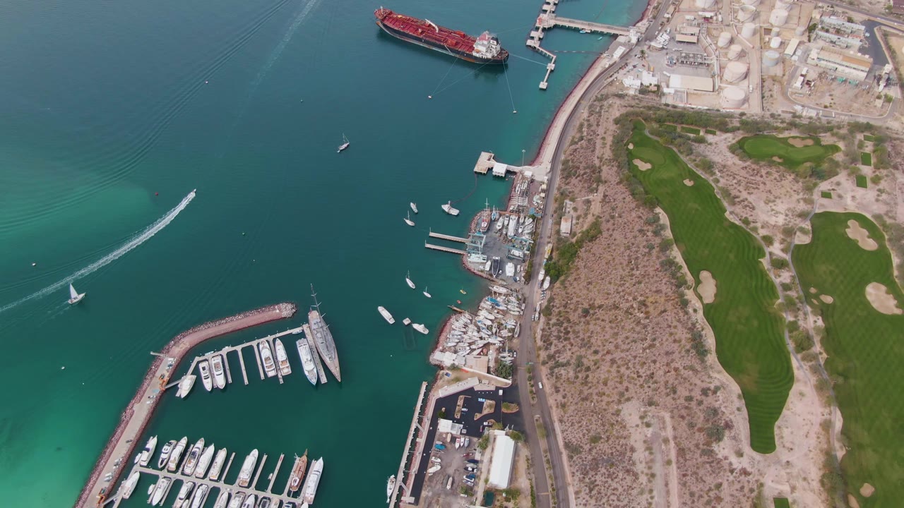 Overhead marina scene with yachts, turquoise water, and speedboat wake