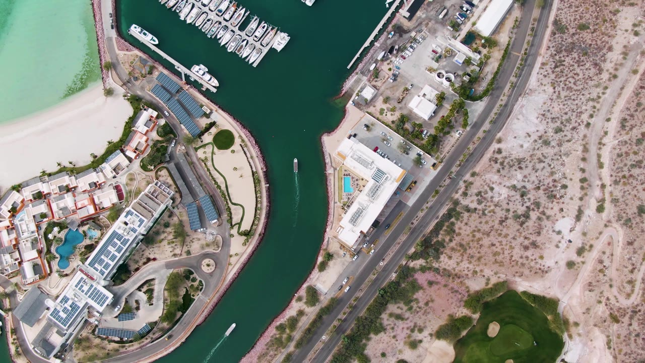 Overhead channel beside beach and buildings with road and dry terrain nearby.