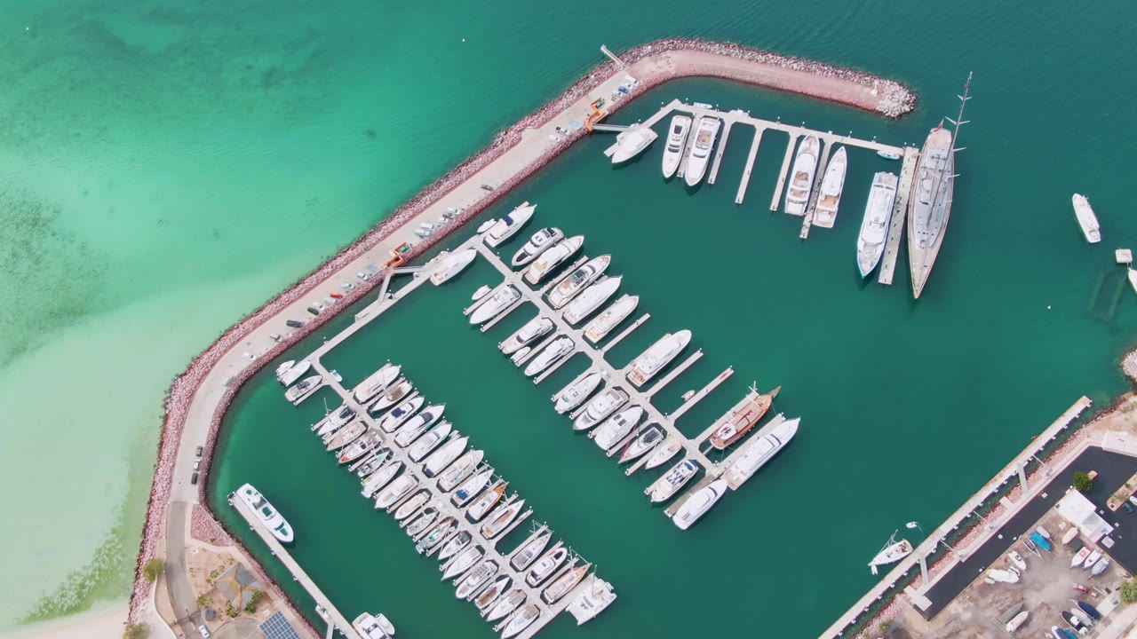 Aerial view of marina slips and boats beside a curved breakwater