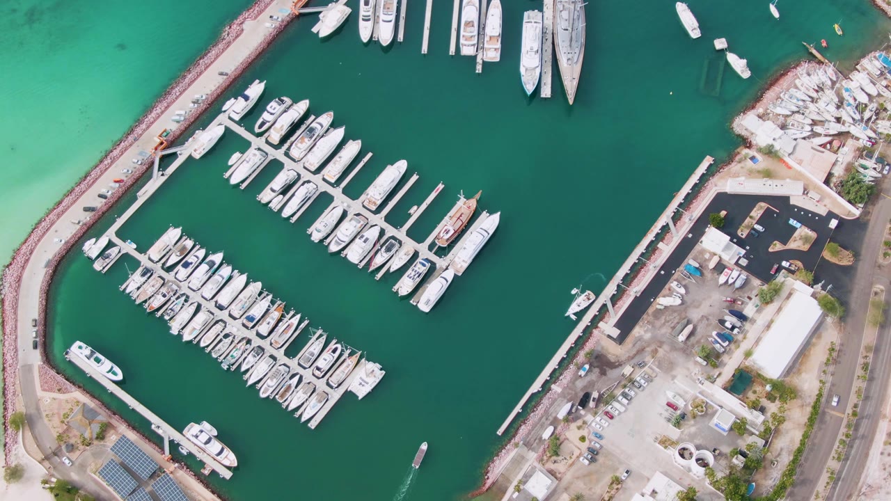 Overhead marina with boat rows, breakwater, and a small craft leaving a wake.