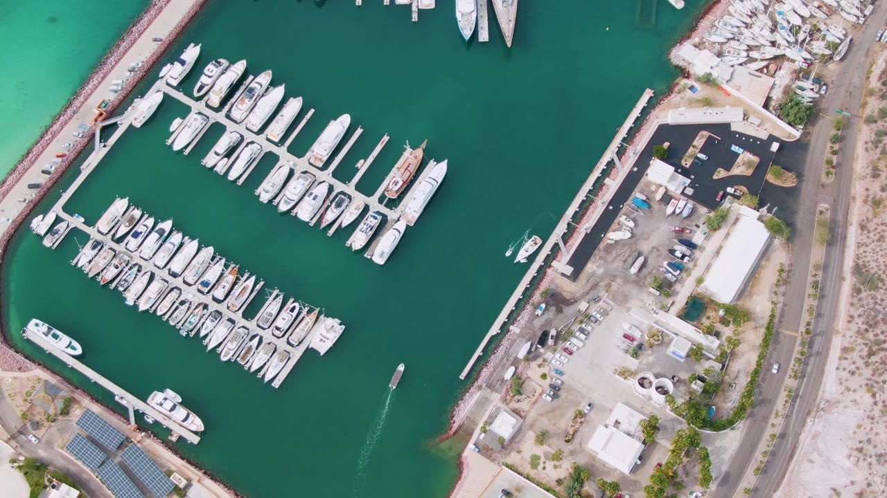 Marina docks with many boats, green water, a road, and shoreline work areas.