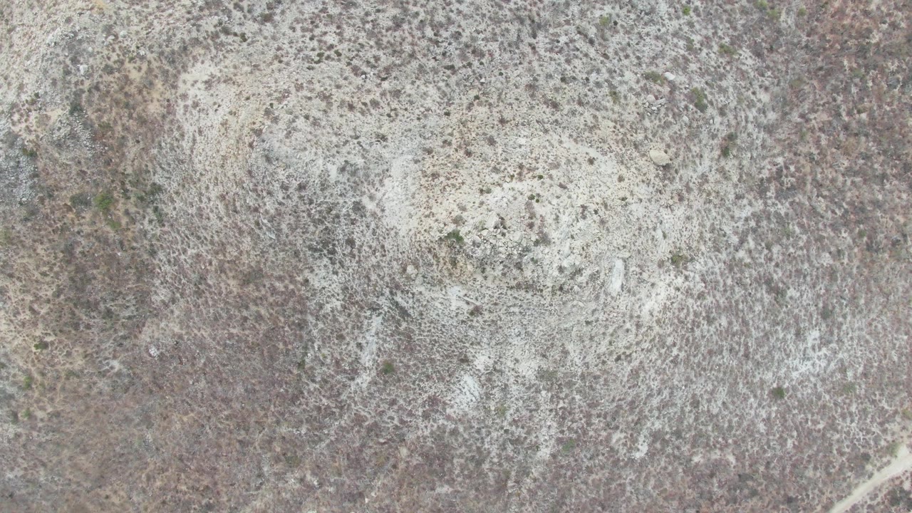 Dry rocky ground with white mineral spread viewed from above