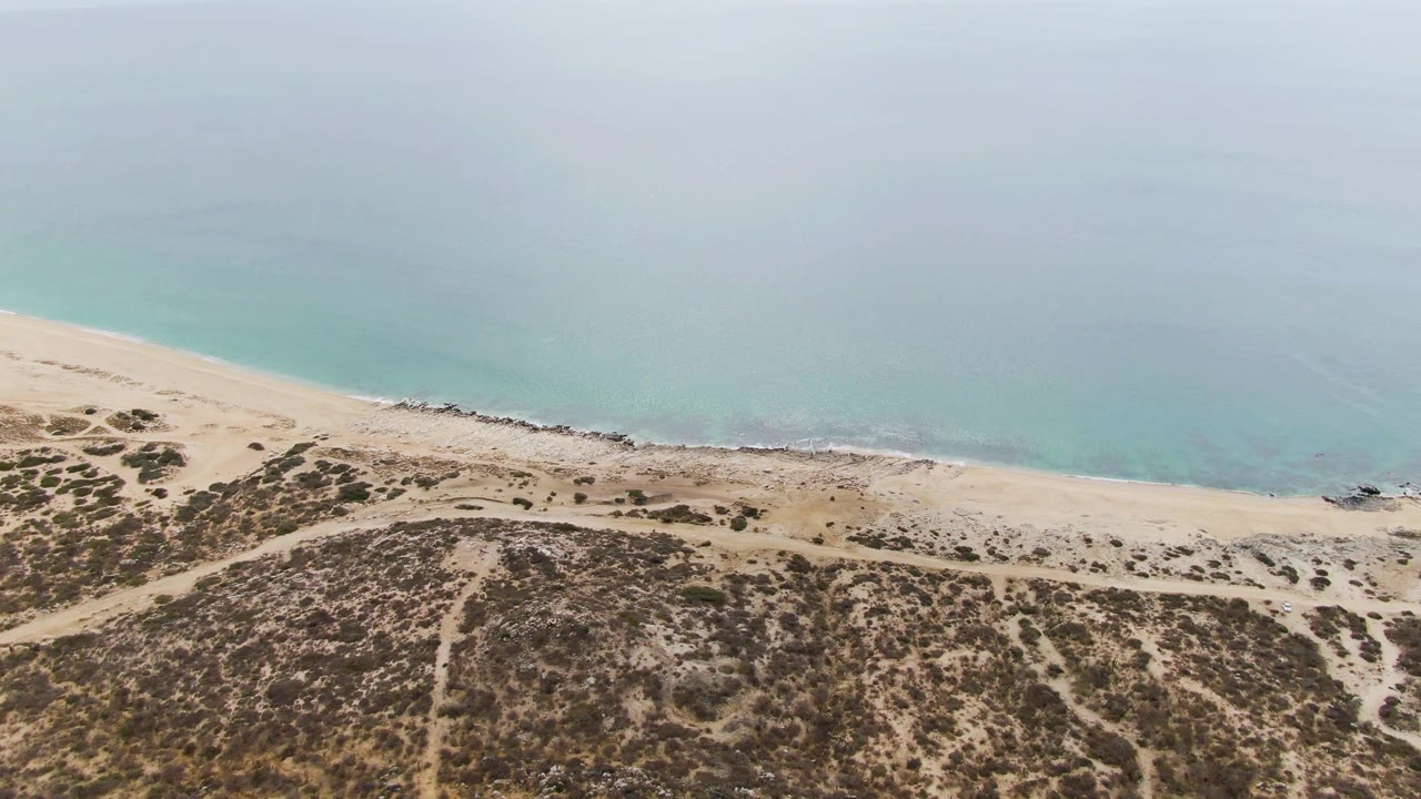 Aerial view of sandy dunes, beach, and turquoise ocean