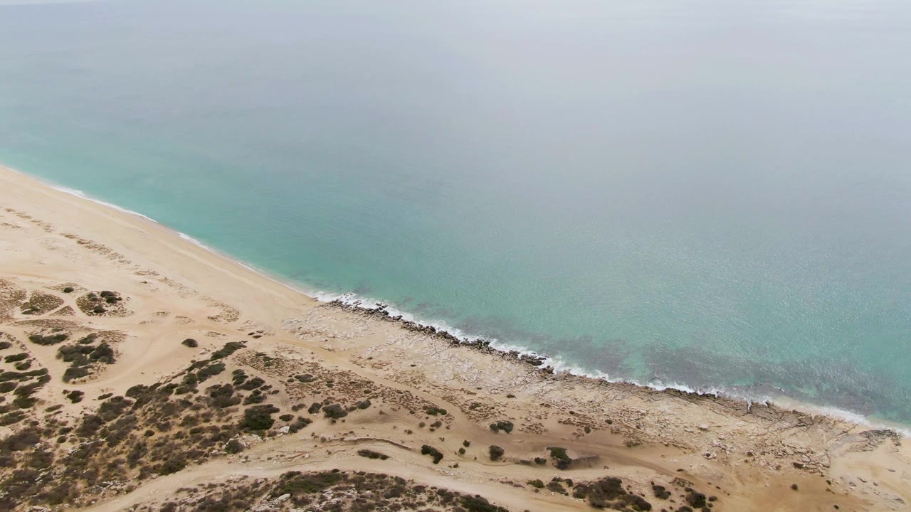 Sandy beach and scrub dunes meeting a turquoise shoreline