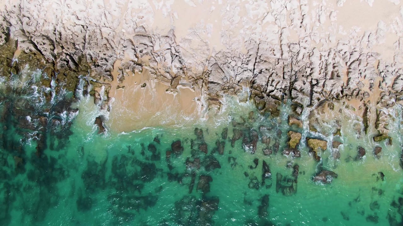 Rocky shoreline with turquoise surf and sandy pocket