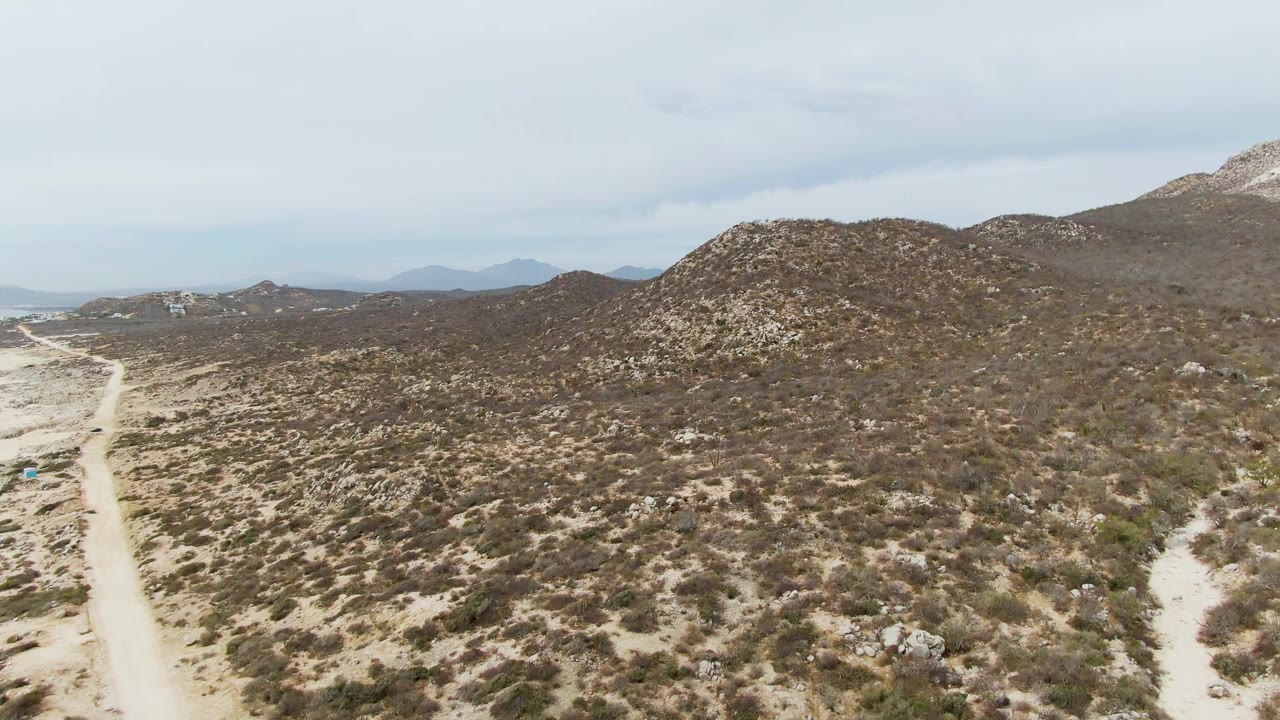 Elevated view of a dirt road beside low desert hills