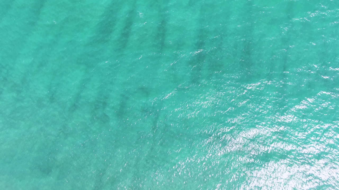 Turquoise sea surface at Puerto Los Cabos Beach shows gentle ripples, muted underwater shadows, and no visible people.
