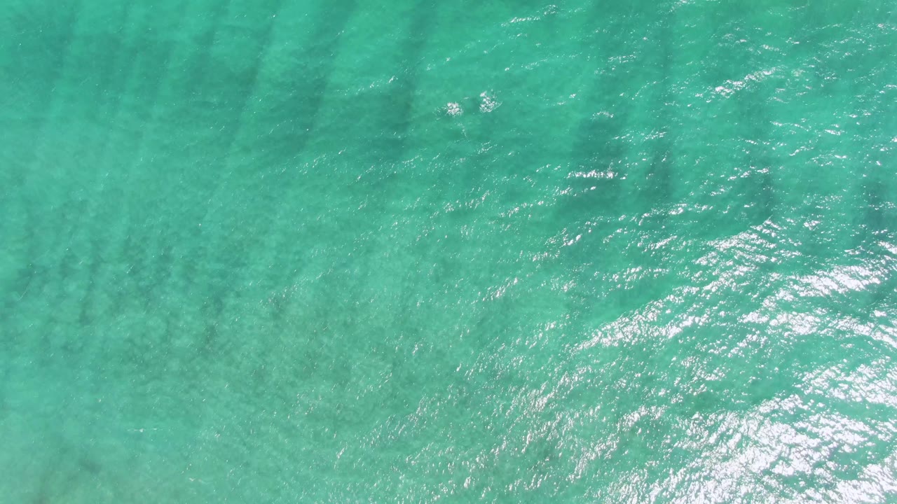 Rippling turquoise sea at Puerto Los Cabos Beach shows darker bands below the surface, scattered white highlights, and no visible people.
