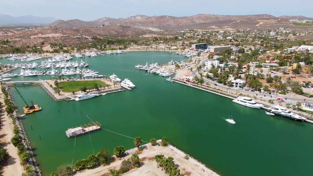 Aerial marina view with a small white boat crossing green water near docked yachts.